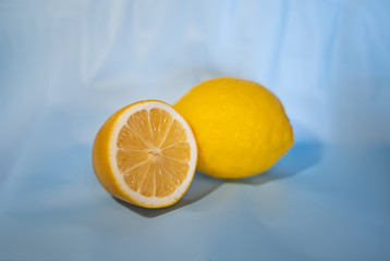 Fototapeta na wymiar Composition with yellow, juicy, sour, fresh, cut two sliced lemons on a blue, delicate, light blue isolated paper background with space for text