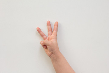 Top view of child hand showing three fingers as number three on the white background