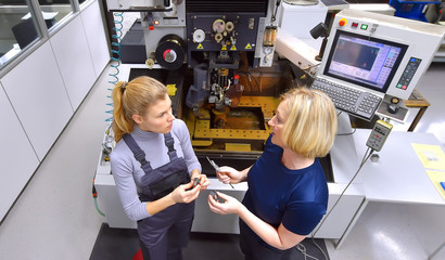 A young trainee receives tuition from her trainer. Both women work as computerized  numerical...