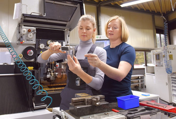 A young trainee receives tuition from her trainer. Both women work as computerized  numerical...
