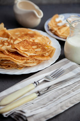 A stack of thin pancakes on a plate. Homemade pastries. Pancakes for breakfast. Appetizing food. Thin pancakes on a plate. Homemade crepes, tasty food. Staple of yeast pancakes.