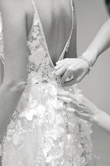 Bridesmaids tie ribbons on the back of the bride's dress.