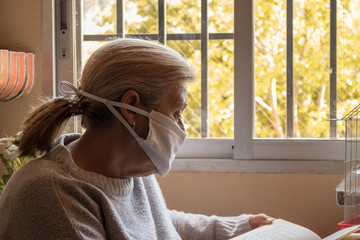 Mujer pasando la cuarentena mientras lee un libro frente a su ventana