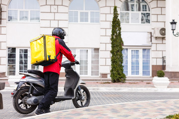 Yellow Delivery Box on Motorcycle with delivery man in front of house.