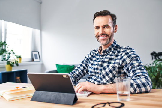 Portrait Of Mid Adult Man Sitting At Desk While Working From Home