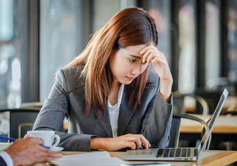 unhappy young businesswoman working on laptop with depression