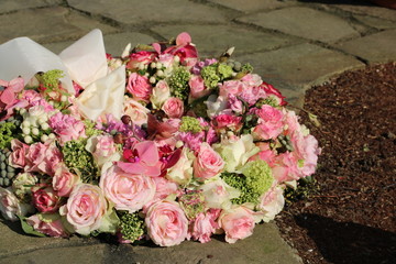Trauerkranz mit rosam Rosen und Blumen auf dem Friedhof nach Beerdigung