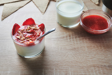 Top view of a homemade natural yogurt with homemade strawberry jam garnished with almonds and strawberry slices
