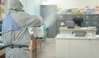 Disinfecting of office to prevent COVID-19, person in white hazmat suit with disinfect in office, coronavirus concept