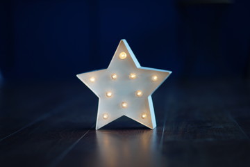 a white star-shaped night lamp on the floor against a dark wall