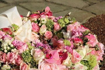Trauerkranz mit rosam Rosen und Blumen auf dem Friedhof nach Beerdigung