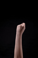 A fist on a black background. Beautiful girl's hand raised up. Minimalism. Protest sign