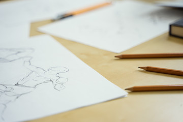 A top view flat lay of many figure drawing pencil and marker sketches. The artist worskspace with male and female drawings and pencils on the white paper, art, craft, creativity, inspiration, concepts