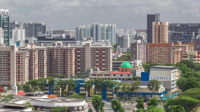 Singapore skyline with Victoria street and shoping mall aerial timelapse. Green trees on the road with traffic. Clouds on a blue sky