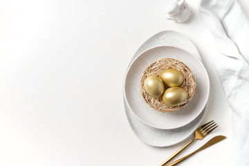 Easter table setting with bunny and golden eggs. Top view.