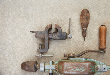 Old construction tools lie on the concrete surface. A set of old tools and a drill.