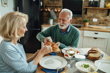 Happy mature couple having lunch together in dining room.