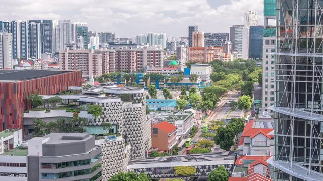 Singapore skyline with Victoria street and National Library aerial timelapse. Green trees on the road with traffic. Clouds on a blue sky