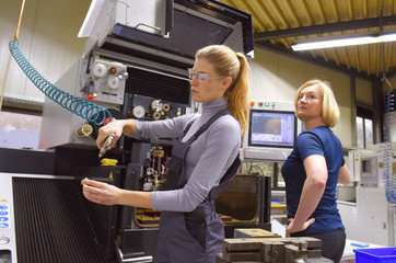 A team of two women work as computerized numerical  control engineers. They are seen together at...