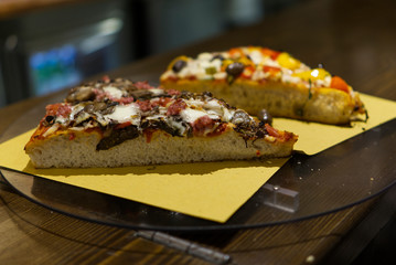 Pizza slices on a yellow napkin on a glass plate