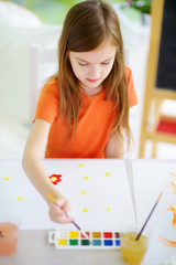 Cute girl drawing with colorful paints. Creative kid painting at home. Education and distance learning for kids. Homeschooling during quarantine. Stay at home entertainment.