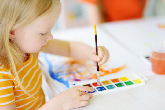 Cute girl drawing with colorful paints. Creative kid painting at home. Education and distance learning for kids. Homeschooling during quarantine. Stay at home entertainment.