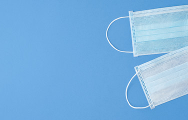Two simple medical masks on a blue background with copy space.