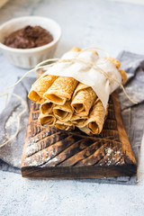 Crepes - sweet thin golden fried pancakes. Vegan, vegetarian dessert. Crepes rolled up into tubes  and chocolate sweet hazelnut dessert cream paste