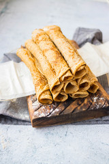 Crepes - sweet thin golden fried pancakes. Vegan, vegetarian dessert. Crepes rolled up into tubes on parchment paper