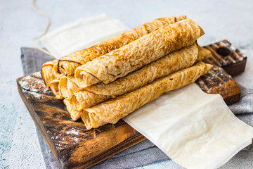 Crepes - sweet thin golden fried pancakes. Vegan, vegetarian dessert. Crepes rolled up into tubes on parchment paper
