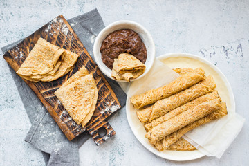 Crepes - sweet thin golden fried pancakes. Vegan, vegetarian dessert. Crepes rolled up into tubes  and chocolate sweet hazelnut dessert cream paste