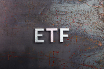 the abbreviation word etf - Exchange Traded Fund - laid with silver letters on raw rusted steel...