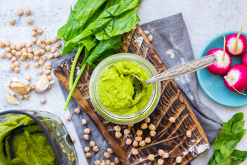 Green spinach chickpea hummus in glass jar. Vegan, vegetarian healthy food.