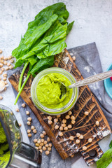 Green spinach chickpea hummus in glass jar. Vegan, vegetarian healthy food.