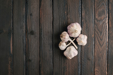 Whole heads of garlic on a dark wooden cutting board.