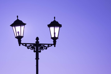 Fototapeta na wymiar Urban landscape. Street lamp with a lamp in a classic style against a purple sky. Beautiful postcard.