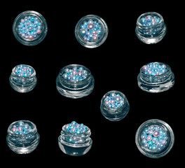Isolated pearl beads in jars on black background