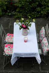 Spring table  with pink flowers and four chairs from above