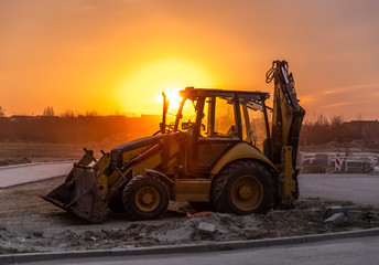 Fototapeta na wymiar Bulldozer parked with no driver at sunset after day work on road construction.
