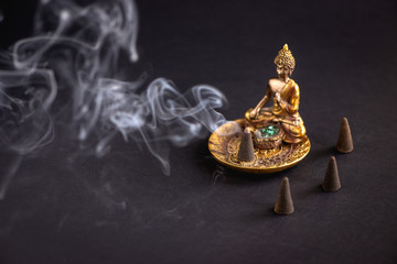 Aromatic cone on beautiful buddha holder burning and creating smoke.