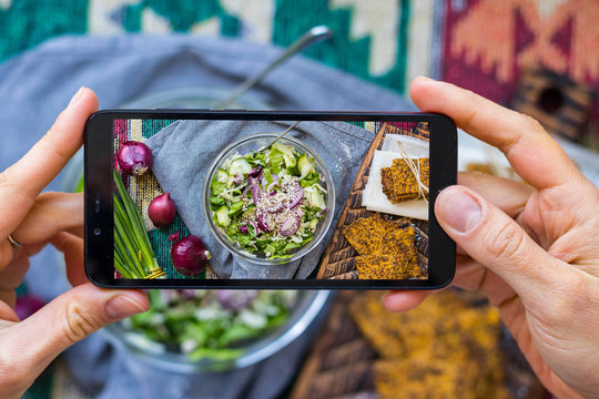 Phone picture of food. Hands make smartphone photography of vegetables detox salad for social media blogging. Concept for online order services. Vegan meal.