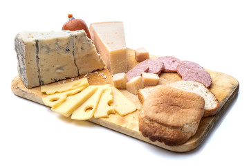 Assortment of various kinds of cheeses served on wooden board with bread and sausages.