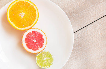 Fresh sliced lemon, lime and orange on a white plate.  Natural Citrus FruitsFresh sliced lemon, lime and orange on a white plate.  Natural Citrus Fruits
