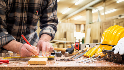 Close-up. Carpenter with pencil and carpenter's square draw the cutting line on a wooden board....
