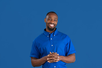 Smiling, laughting. Monochrome portrait of young african-american man isolated on blue studio...