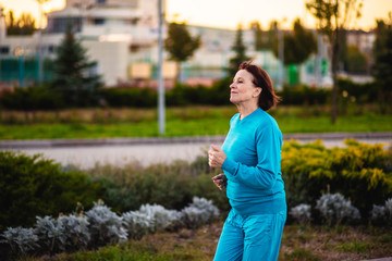 Fototapeta premium An elderly woman goes in for sports at sunset.