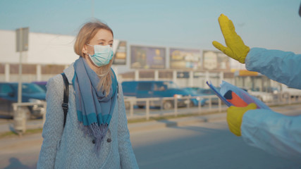 Medical worker in a protective suit screening passenger to check the Covid-19 symptoms coronavirus...