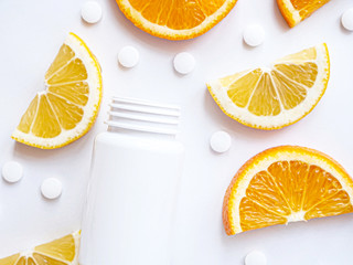 scattered vitamin pills and bottle with lemon orange on white background. Flat lay. Concept boost immune system, medicine and tablets.