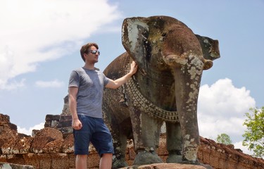 Ruins of Angkor, man with stone elephant statue before blue sky, Ta Keo, Angkor Wat, Cambodia