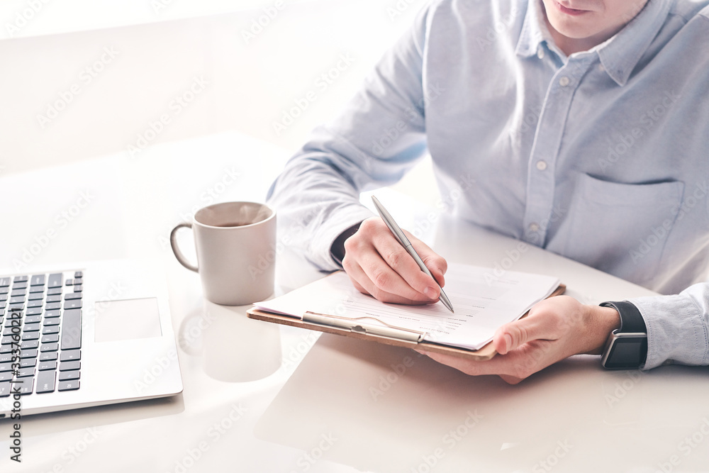 Poster Close-up of busy man returned from foreign travel sitting at table and filling form